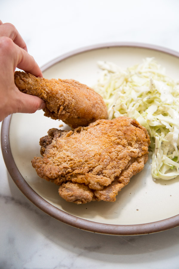 gluten-free fried chicken thigh and drumbstick on a plate with slaw