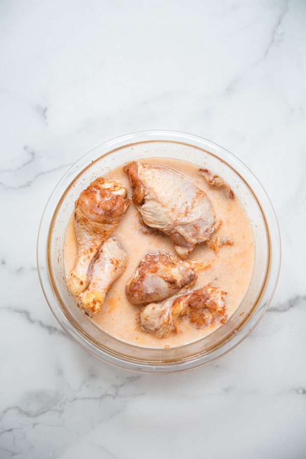 gluten-free chicken marinating in buttermilk and spices in a bowl