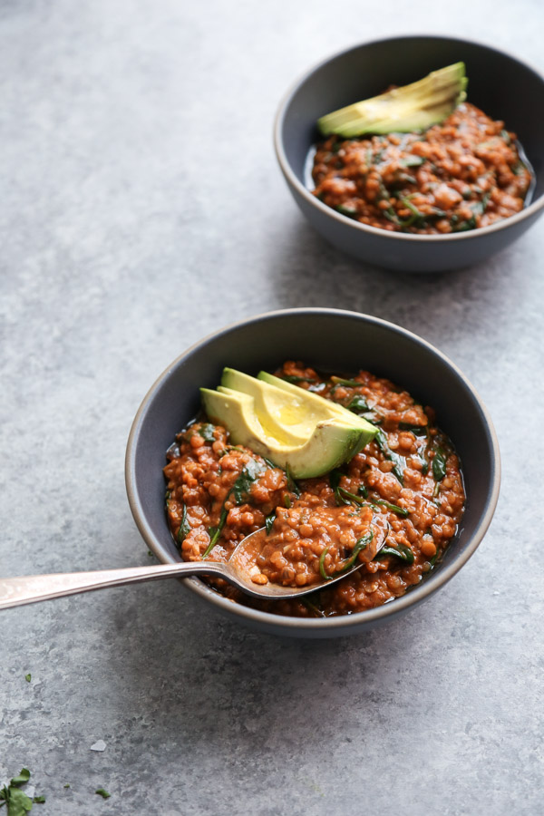 Red lentil curry with spinach in a bowl with spoon