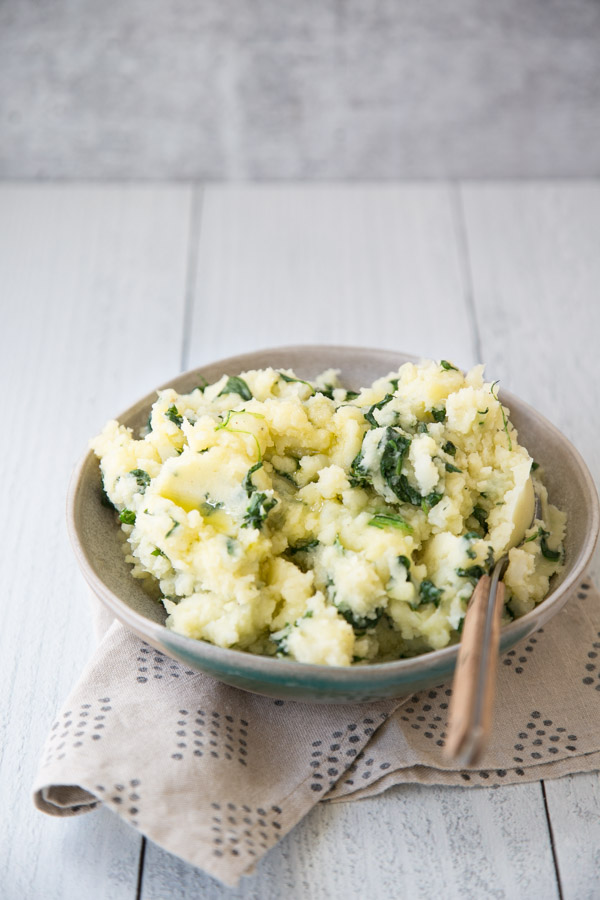 gluten-free spinach mashed potatoes in a bowl with spoon on top of napkin 