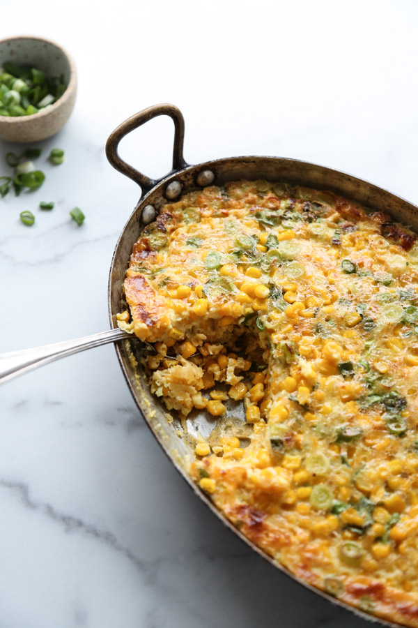 healthy corn pudding with scallions in a casserole pan