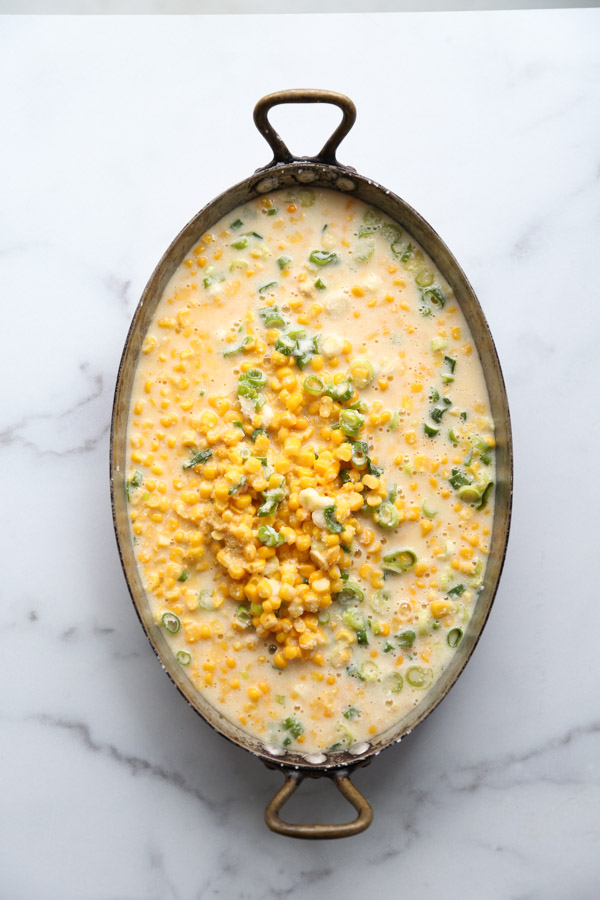 healthy corn pudding with scallions in a casserole pan overhead