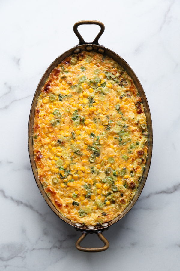dairy-free corn pudding with scallions in a casserole pan after getting baked in the oven