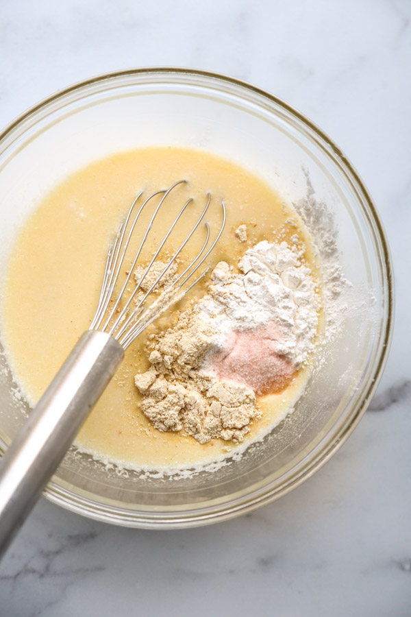 cornmeal and dry ingredients added to dairy-free wet ingredients in a bowl