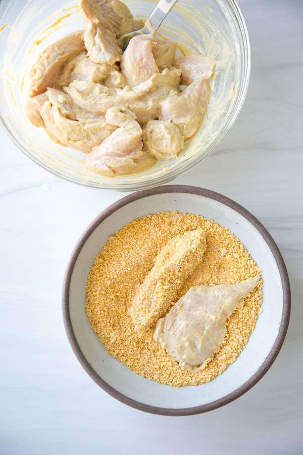 gluten-free chicken tenders dredged in cornflake crust in a bowl