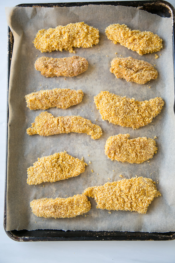 gluten-free chicken strips coated in cornflakes on a sheet pan