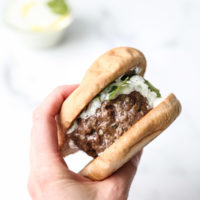 holding greek lamb burger in gluten-free bun