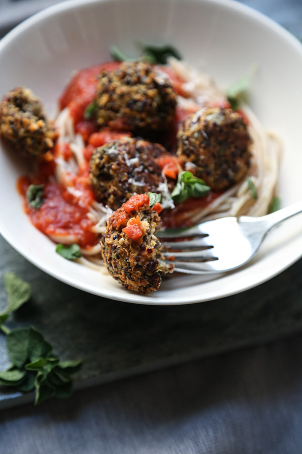 Fork holding Meatless Meatballs from the side in a bowl with spaghetti and tomato sauce