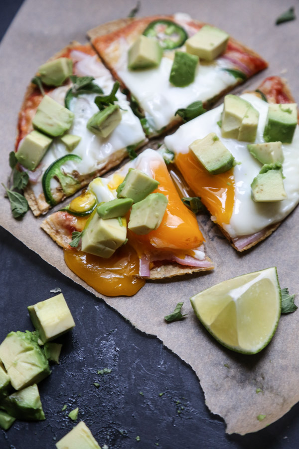 gluten-free breakfast pizza on parchment with egg and avocado on top