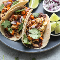 These vegetarian black bean tacos are made with chile-spiked refried beans, roasted sweet potato- leek hash, and spicy chipotle tahini sauce. Easy + delish! | Feed Me Phoebe