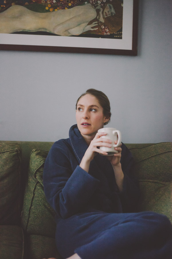 the author Phoebe Lapine sitting with a mug of caffeine-free tea on the couch 