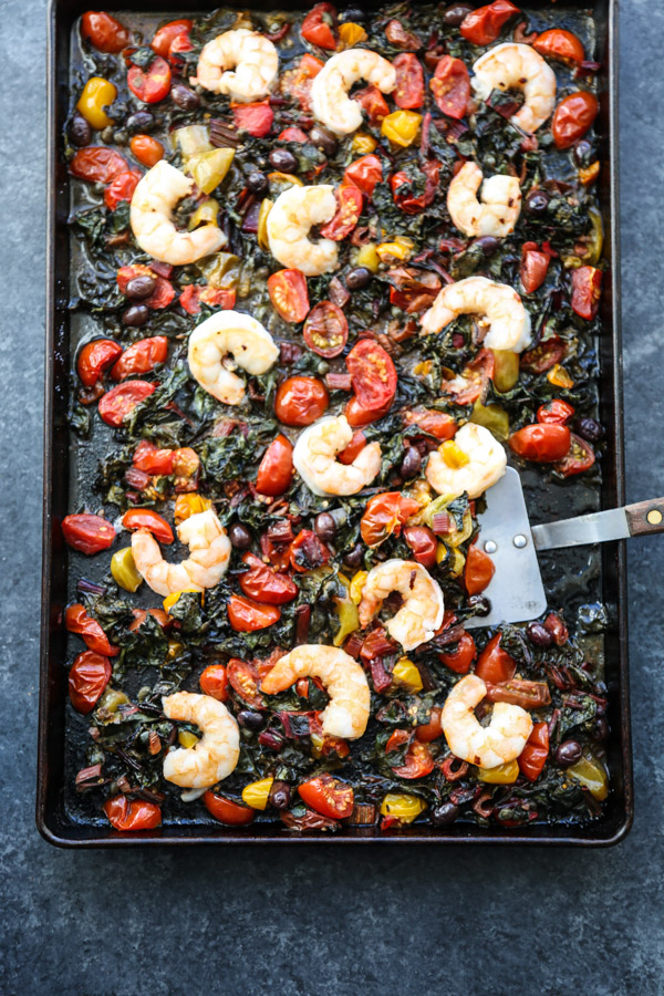 A sheet pan full of shrimp, cherry tomatoes, chard, puttanesca sauce.