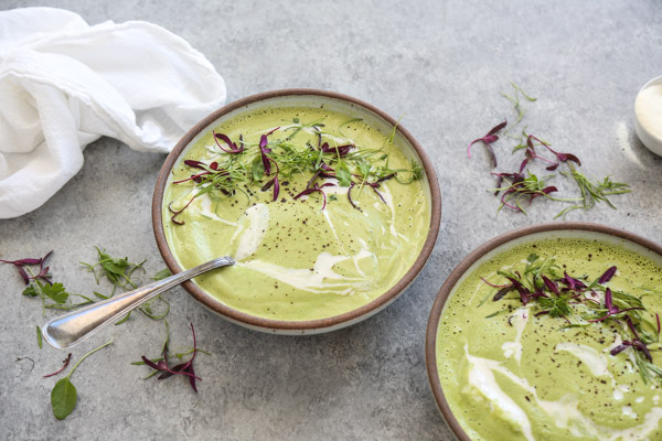 Green Asparagus Soup in a bowl with herbs.