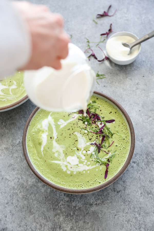 Green Asparagus Soup in a bowl with herbs.