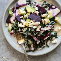 kale salad with beets and avocado on a plate with fork