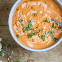 bowl of cream of tomato soup with a spoon and basil