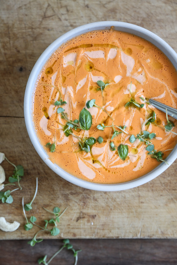 bowl of cream of tomato soup with a spoon and basil
