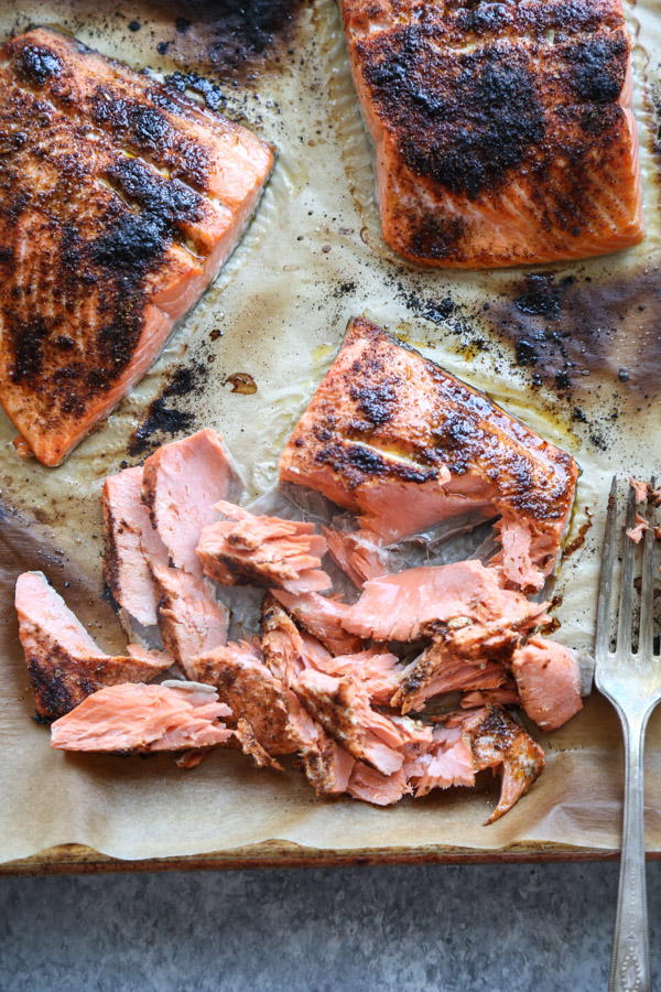 blackened salmon on a sheet pan with parchment paper flaked