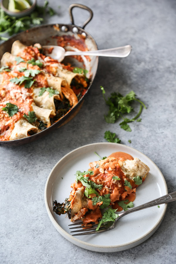 Gluten-free chicken enchiladas on plate with dairy-free red sauce and fork