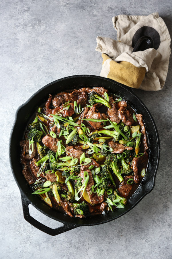 mongolian beef in a skillet with spatula and scallions