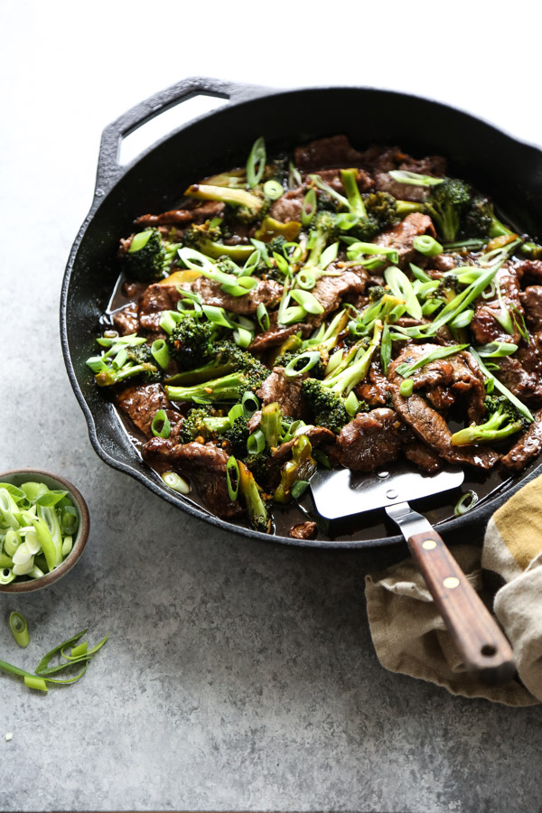 mongolian beef in a wok with spatula and scallions