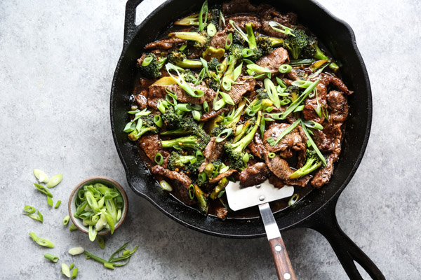 mongolian beef in a wok with spatula and scallions