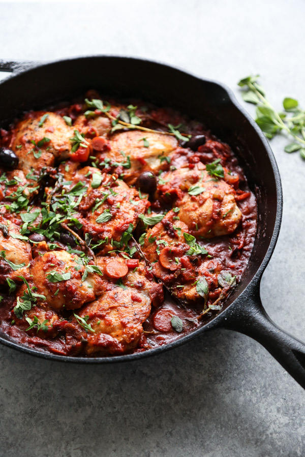 chicken cacciatore in a skillet with oregano and parsley