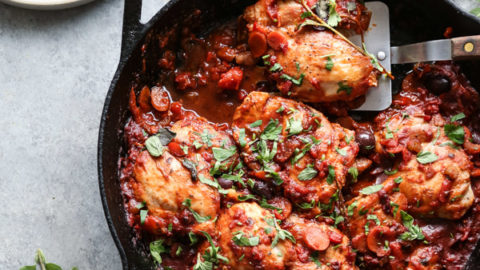 chicken cacciatore in a skillet with a spatula on a plate