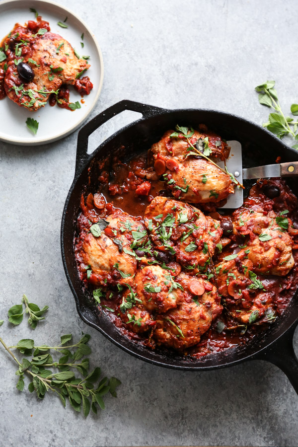 low FODMAP chicken cacciatore in a skillet with a spatula on a plate