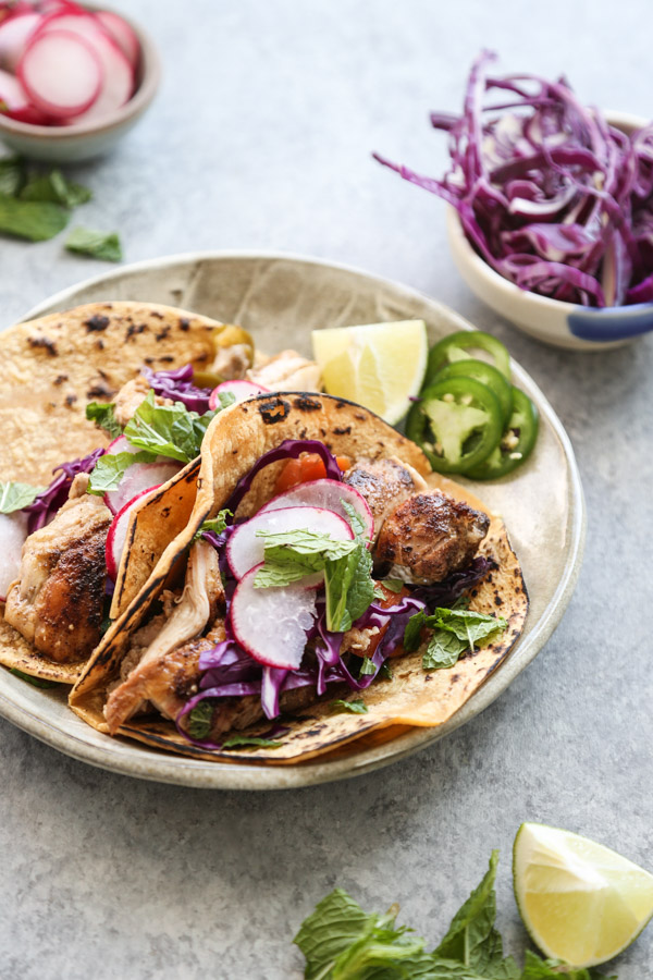 Low fodmap chicken tacos on a plate with cabbage and jalapeno garnish side view