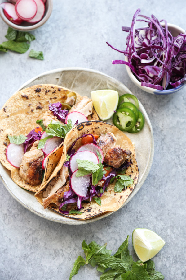 Low fodmap chicken tacos on a plate with cabbage and jalapeño garnish