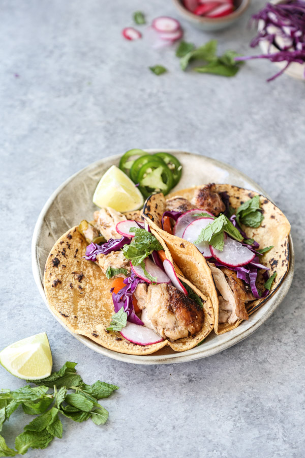 low fodmap chicken tacos on a plate with cabbage and jalapeno garnish