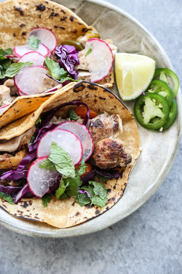 low fodmap chicken tacos on a plate with cabbage and jalapeno garnish