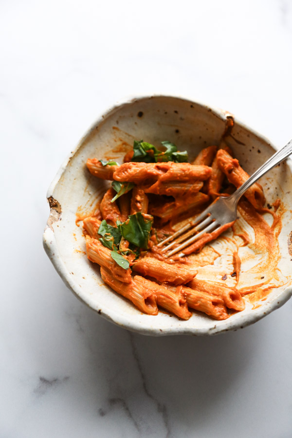 Gluten-Free penne with low FODMAP vodka sauce in a bowl half eaten with fork