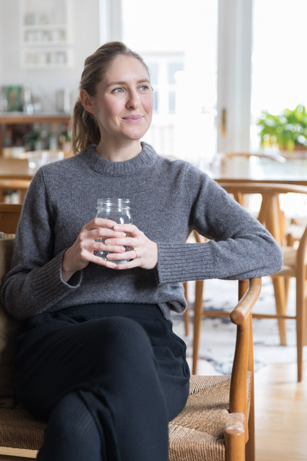 The author Phoebe Lapine sitting in a chair with a glass of water