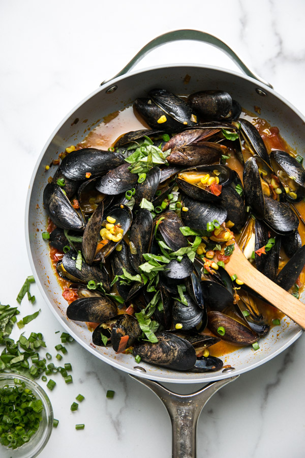 Mussels with red sauce and corn in a pan