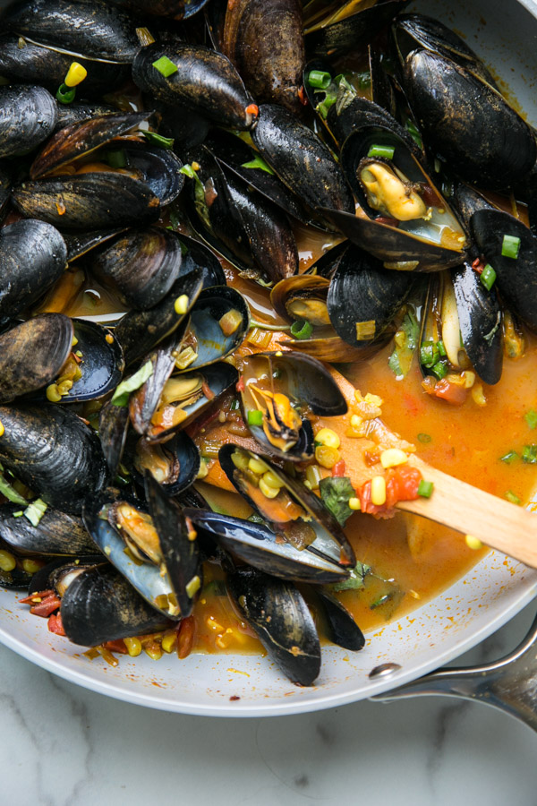 Mussels with red sauce and corn in a pan