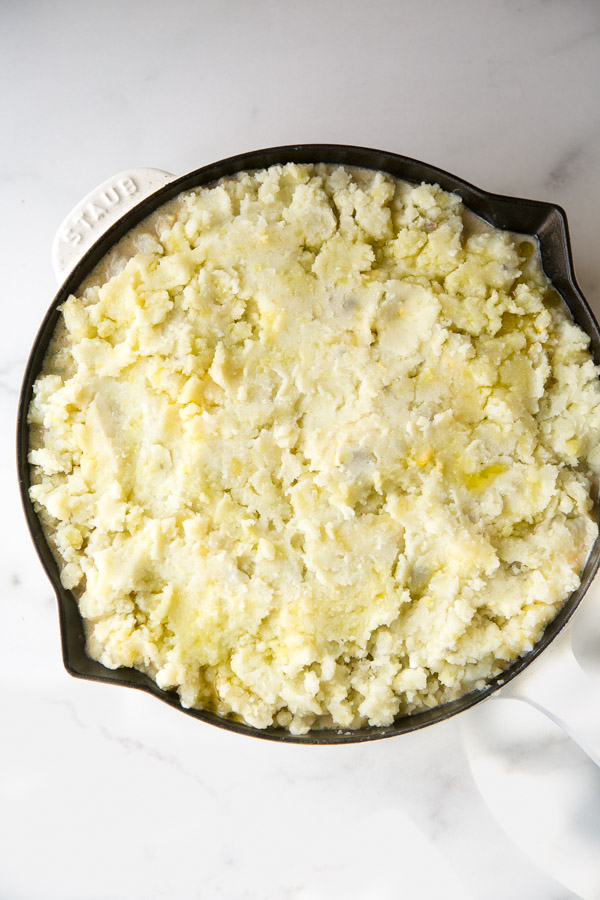 dairy-free fish pie topped with potatoes in a skillet before the oven