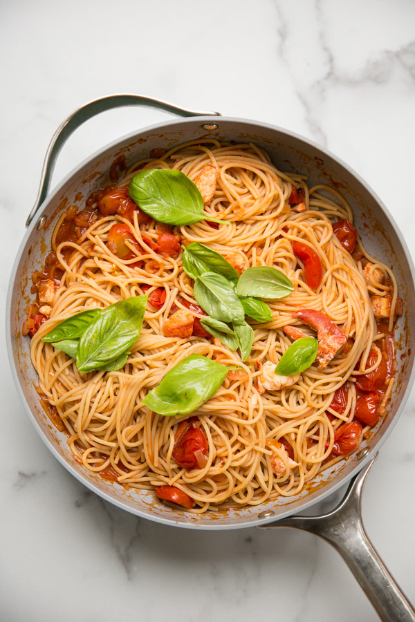 gluten-free pasta in a skillet with tomatoes and basil