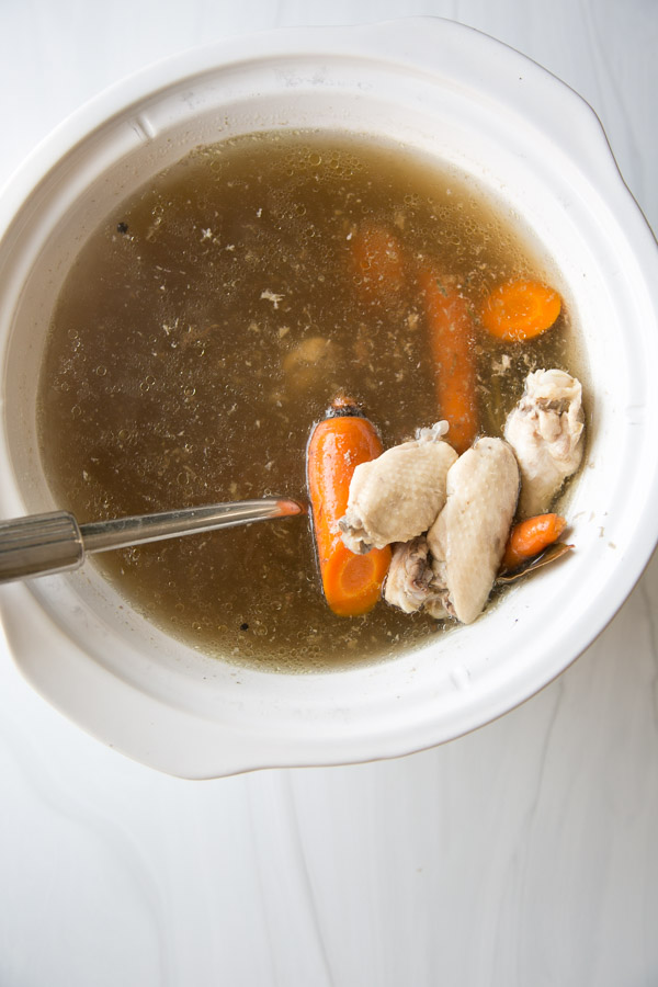 Low FODMAP chicken broth in a slow cooker with chicken wings and carrots