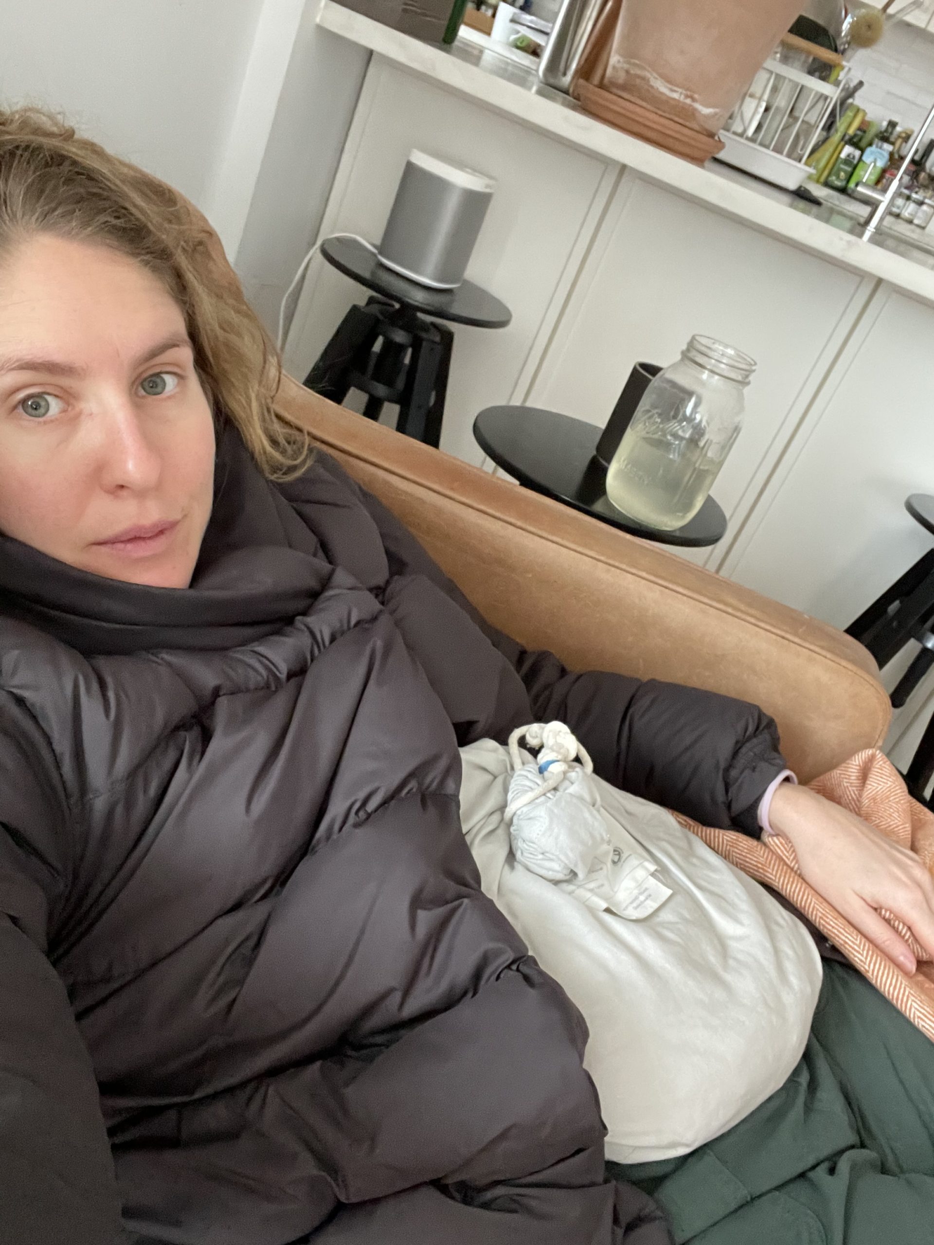 woman with a heating pad on the couch recovering after egg retrieval