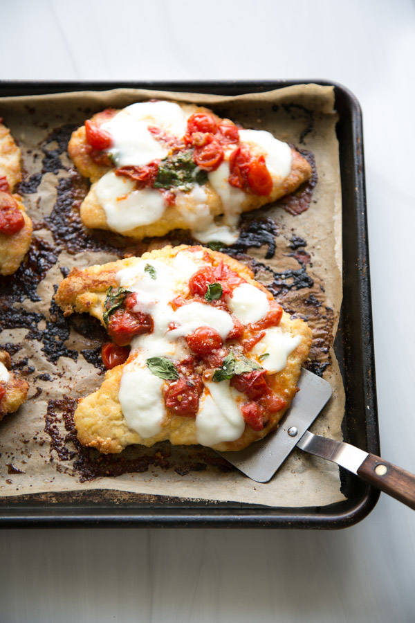 Baked Gluten-Free Chicken Parmesan on a sheet pan with spatula under one breaded chicken breast
