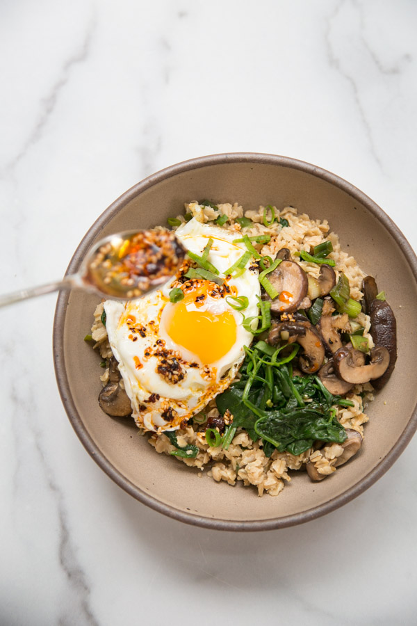 spoon topping savory oatmeal with chili crisp in a bowl