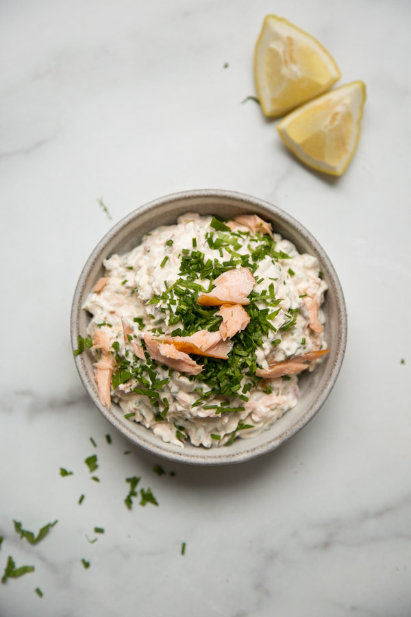 Smoked Salmon Dip in a bowl with chive garnish and lemon wedges