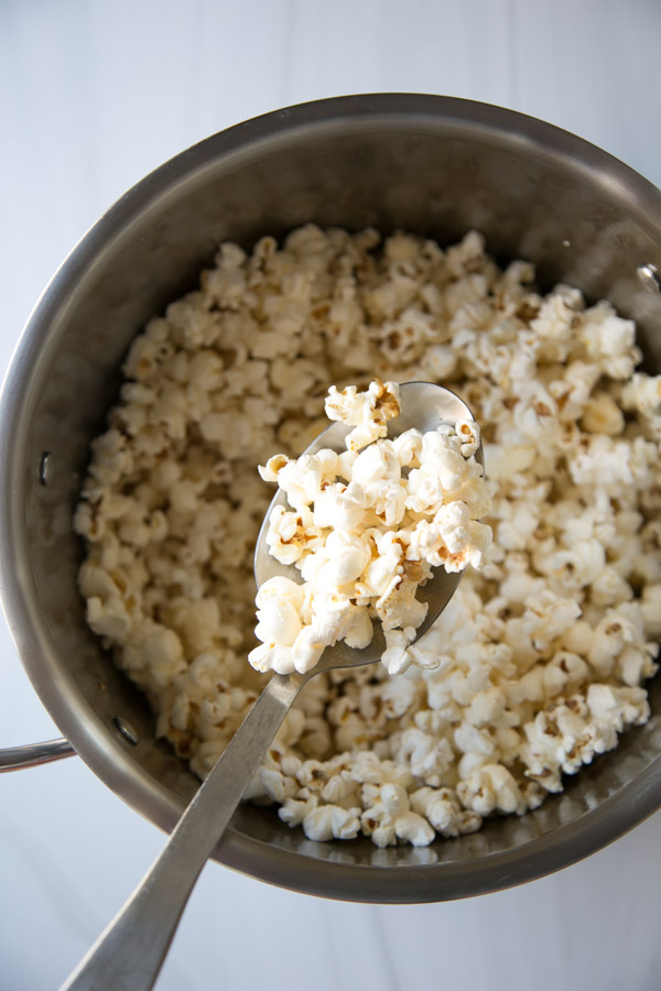 Spoon popping gluten-free popcorn into pot