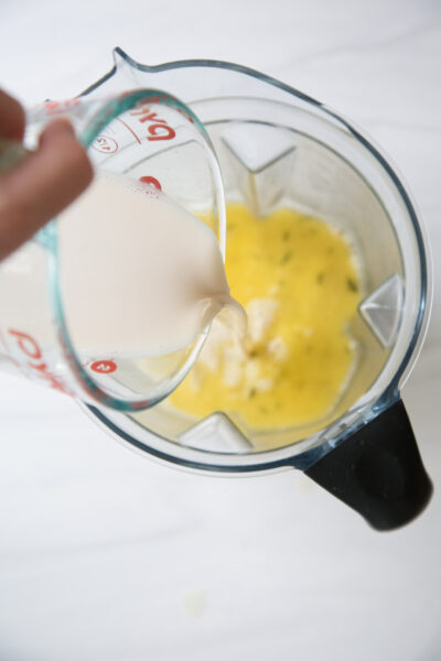 cup measure pouring dairy-free milk into blender