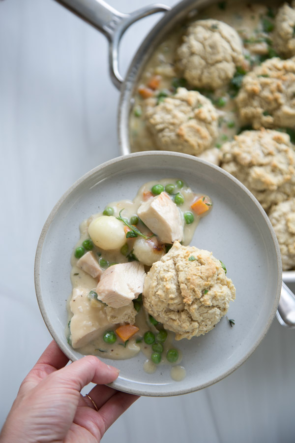 hand holding a plate of gluten-free dairy-free chicken pot pie with GF biscuit topping