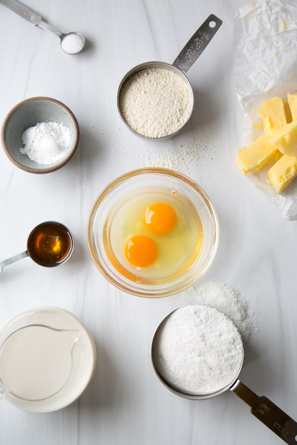gluten-free cornbread ingredients on a marble counter" salt, honey, eggs, butter, cornmeal, white rice four, milk