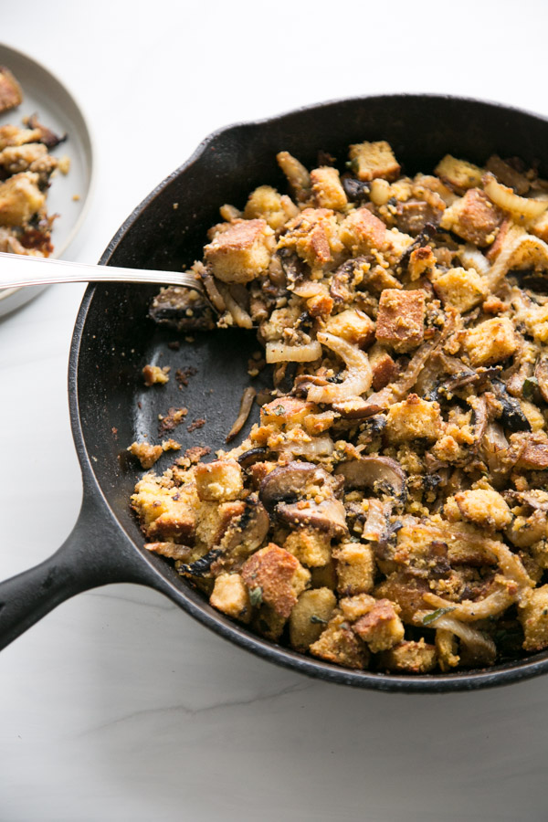 skillet holding gluten-free cornbread stuffing with a spoon