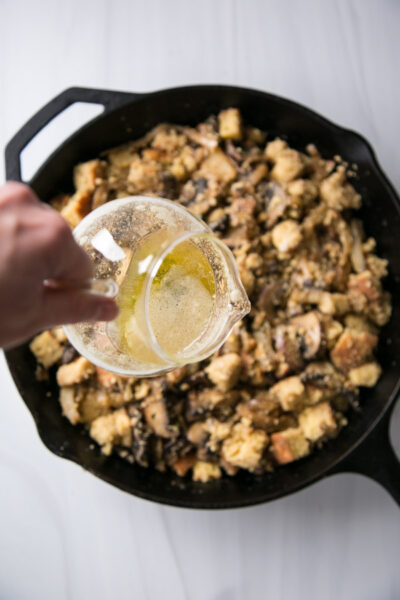 hand pouring sage butter over gluten-free cornbread dressing